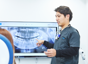 レントゲン画像を使って説明する歯科医師